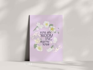 Floral lettering design on a soft lavender background, featuring white and pale pink flowers and green foliage arranged around the words “You Are Blooming Marvelous.”